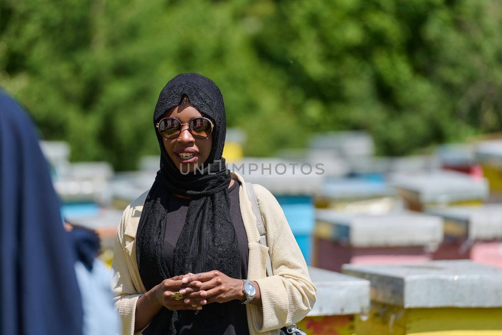 African American Muslim woman in hijab explores natural bee farms for honey production, blending tradition with sustainability in the serene countryside.