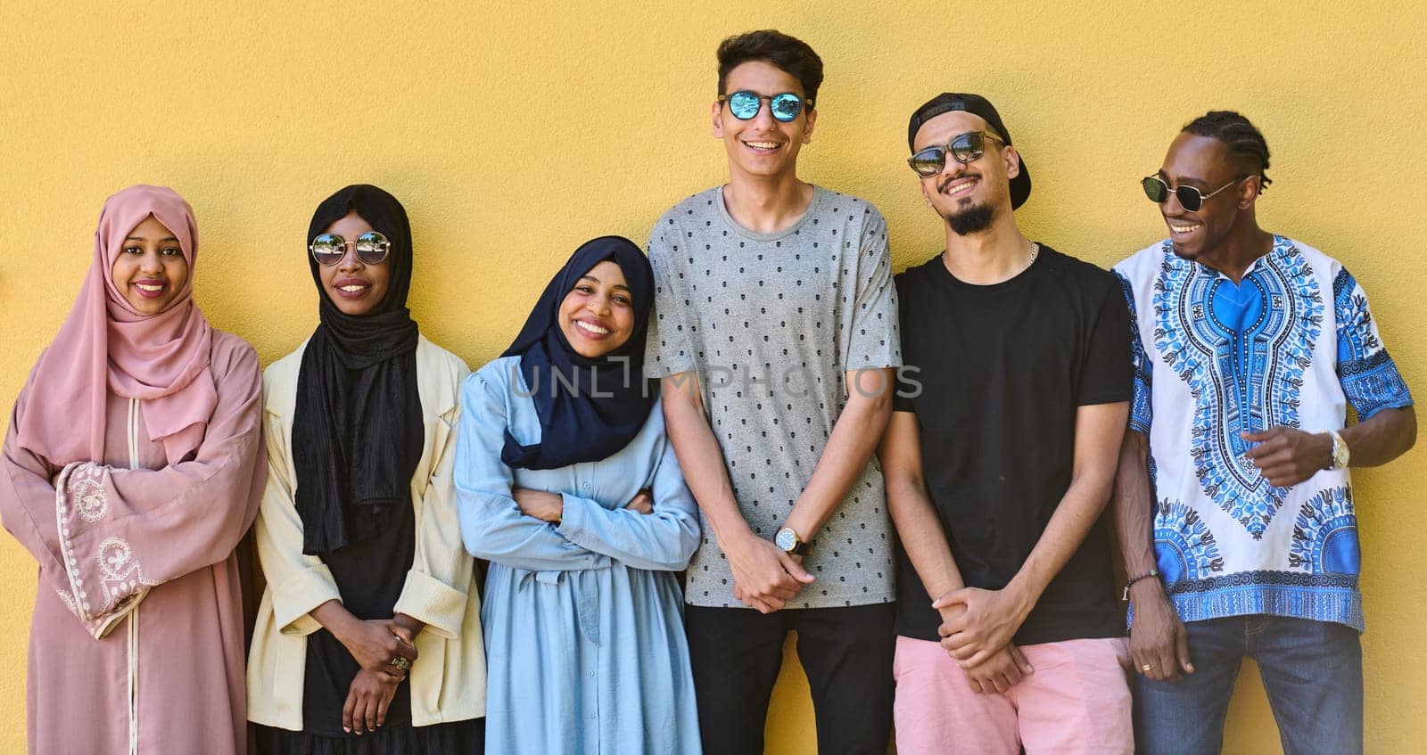 A diverse group of African-American and Middle Eastern teenagers stand confidently in front of a vibrant yellow wall, showcasing unity and urban style