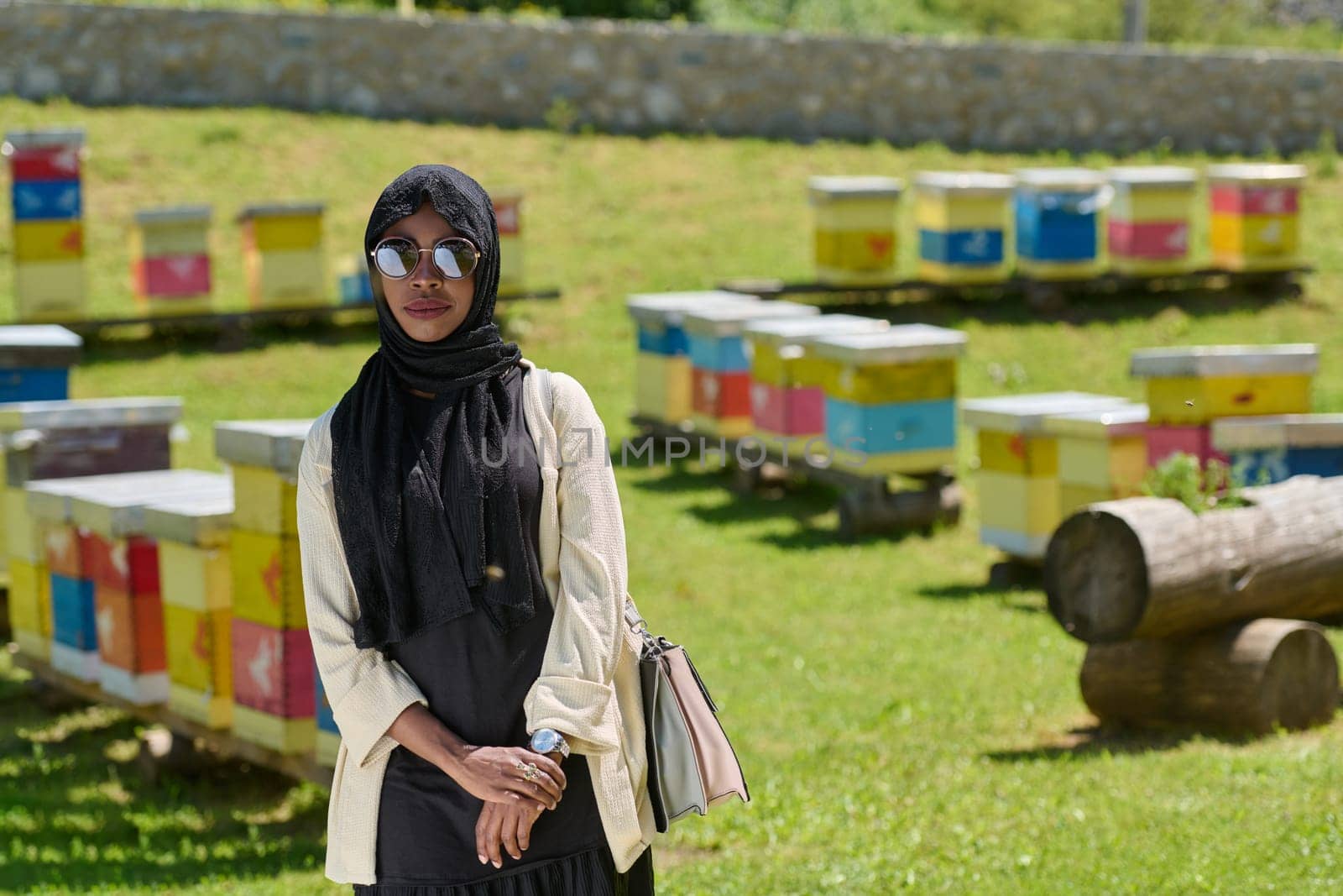 African American Muslim woman in hijab explores natural bee farms for honey production, blending tradition with sustainability in the serene countryside.