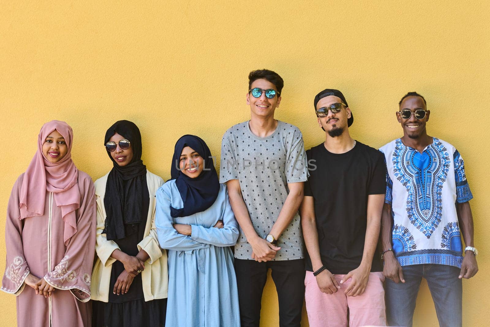 A diverse group of African-American and Middle Eastern teenagers stand confidently in front of a vibrant yellow wall, showcasing unity and urban style