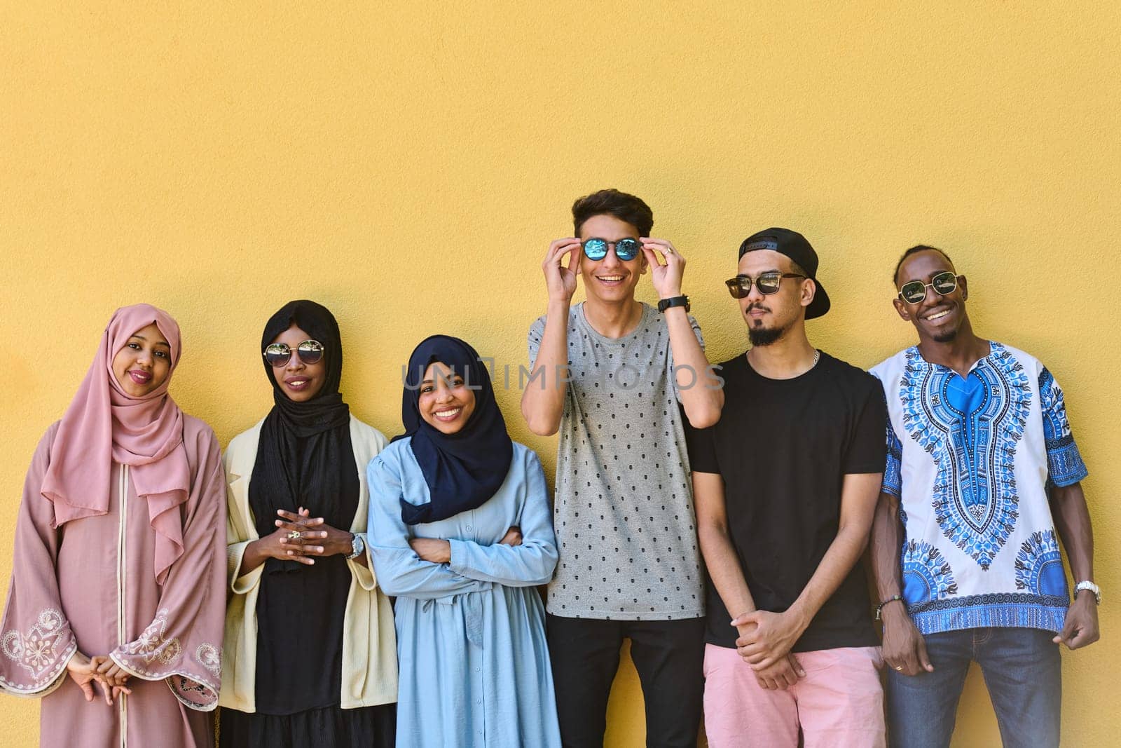 A diverse group of African-American and Middle Eastern teenagers stand confidently in front of a vibrant yellow wall, showcasing unity and urban style