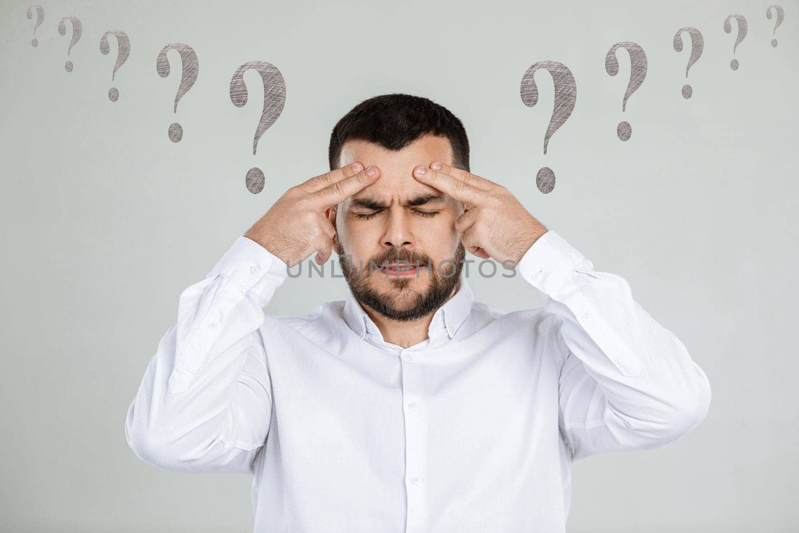 portrait of doubtful bearded man in white shirt asking questions on gray background.