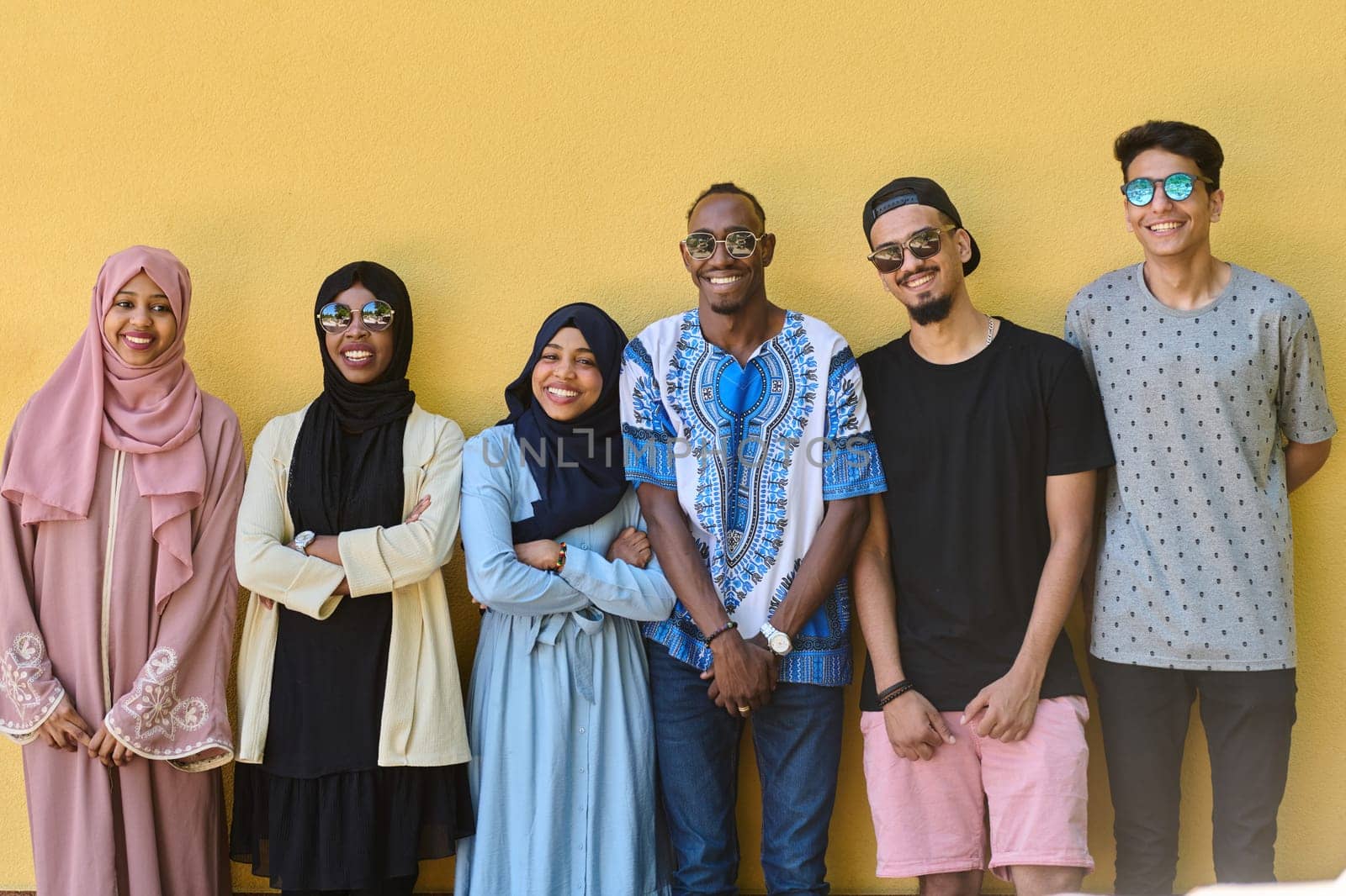 A diverse group of African-American and Middle Eastern teenagers stand confidently in front of a vibrant yellow wall, showcasing unity and urban style