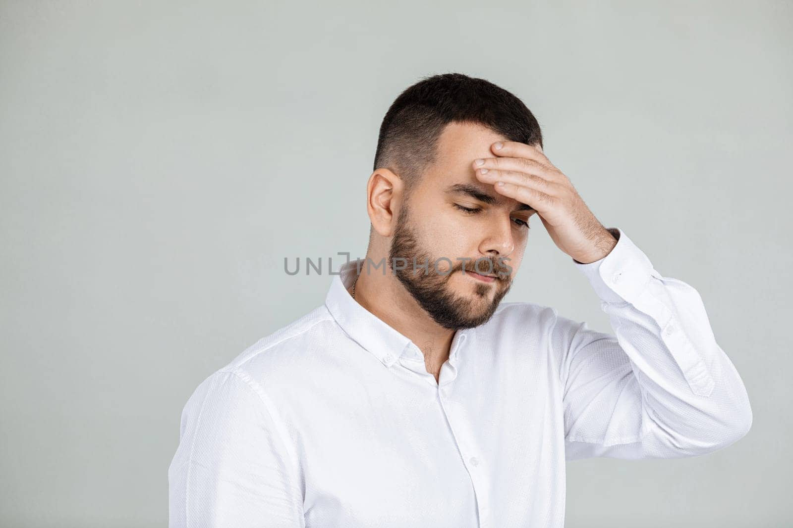 portrait of calm thoughtful bearded man in white shirt on gray background. man thinking about things