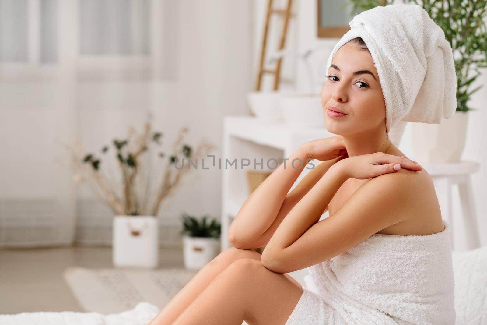 beautiful young woman with bath towel sitting on bed. copy space
