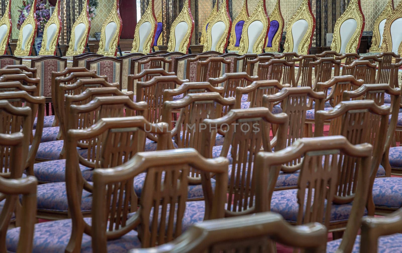 Bangkok, Thailand - May 22, 2024 - Perspective view of Wooden chairs with cushion seat and Pulpit within Samphanthawong Saram Worawihan temple. Space for text, Selective focus.