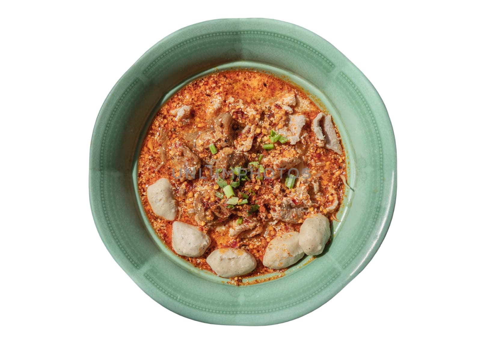 Spicy tom yum rice stick noodles (Thai spicy soup) with braised pork (stewed pork), fresh pork and pork balls sprinkled with Coriander, Chopped onions and pepper in Green ceramic bowl isolated on white background with clipping path. Top view, Space for text, Selective focus.