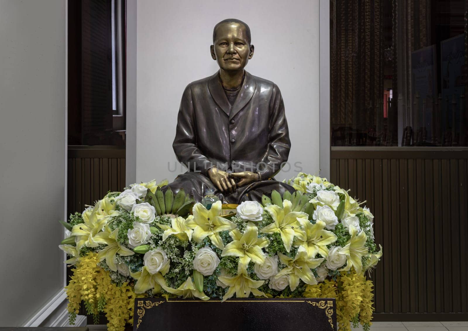 Bangkok, Thailand - May 22, 2024 - Statue of Khun Mae Boon Reun Tongboonterm, Sitting on the bouquet of green lily and white rose flowers at Samphanthawong Saram Worawihan temple (Wat Ko). Space for text, Selective focus.