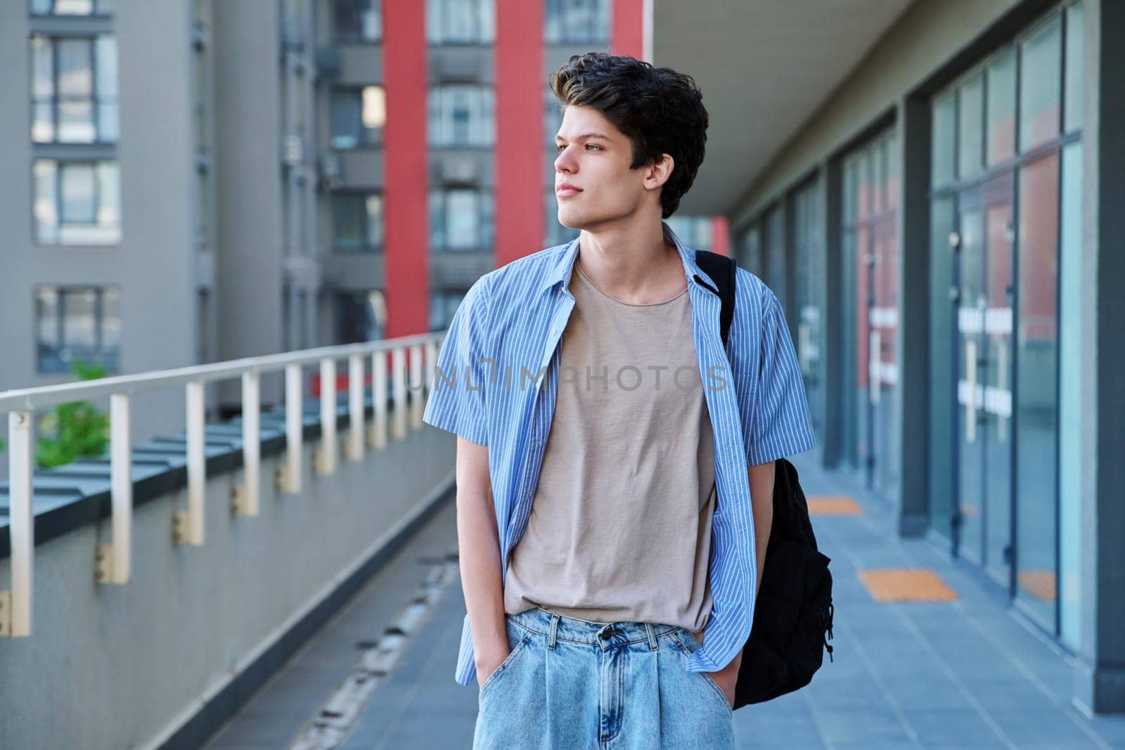 Portrait of confident smiling handsome college student guy, young handsome male with backpack looking at profile, urban outdoor. Education, lifestyle, 19,20 years age youth concept