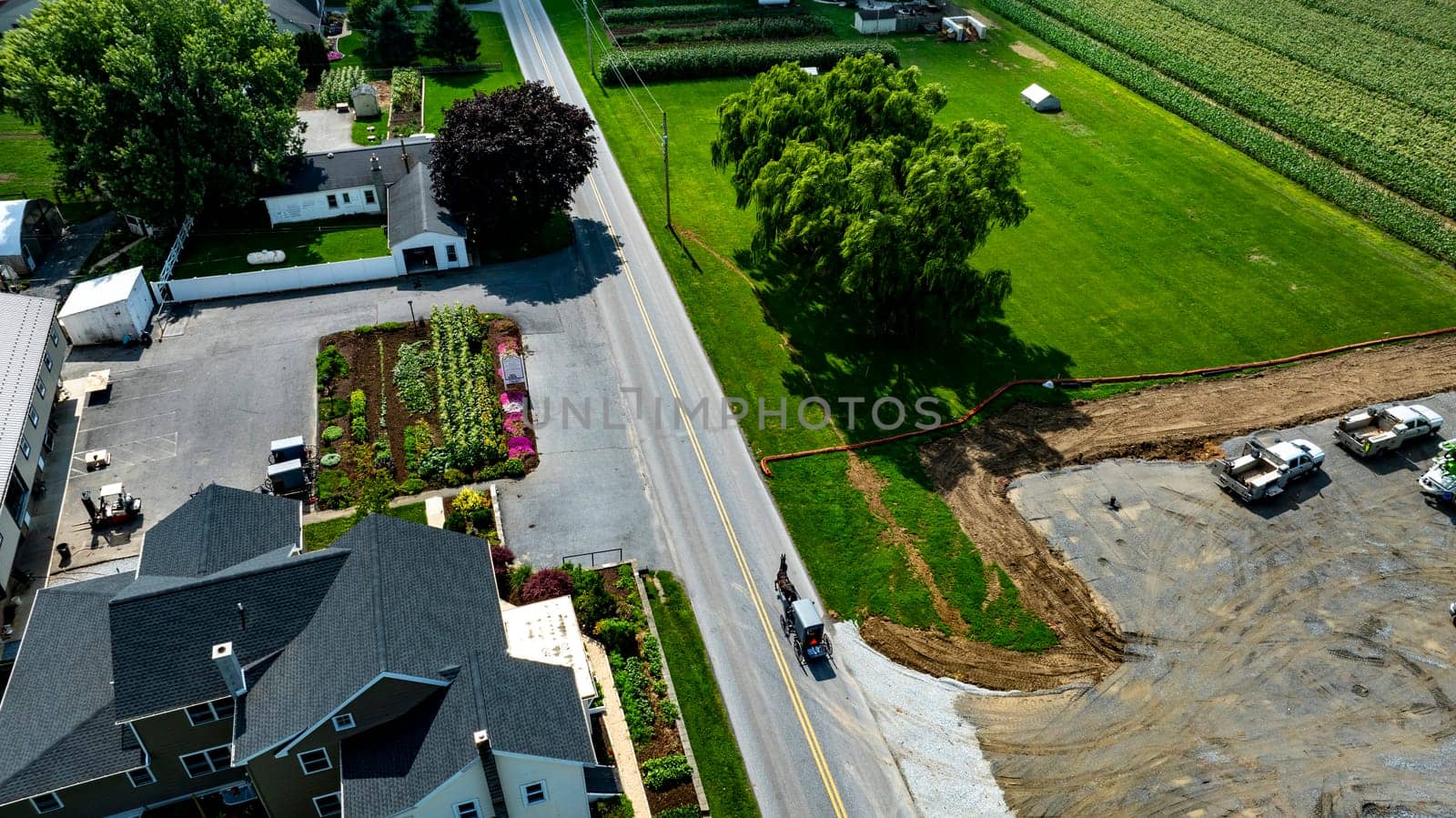 An Aerial View of Roadside Property with Garden and Construction Area and an Amish Horse and Buggy