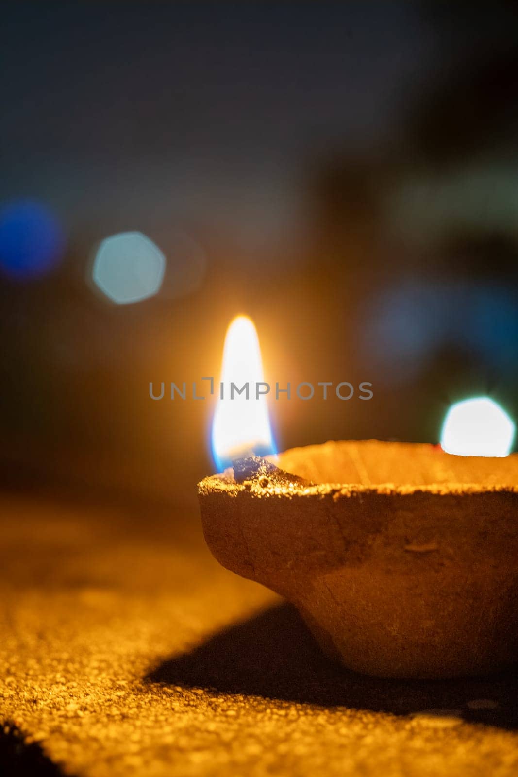 handmade earthenware clay coconut fiber diya lamp lit in front of the soft focussed bokeh lights of diwali major celebration in India
