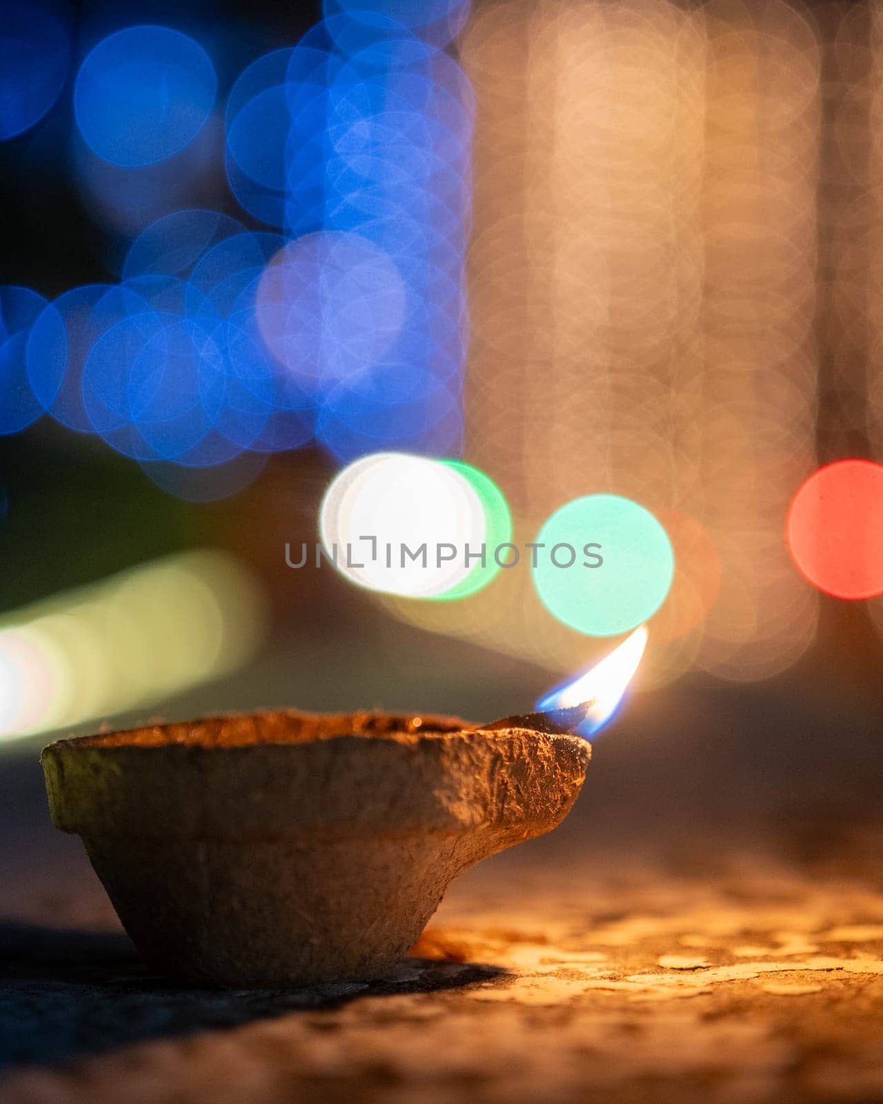 handmade earthenware clay coconut fiber diya lamp lit in front of the soft focussed bokeh lights of diwali major celebration in India