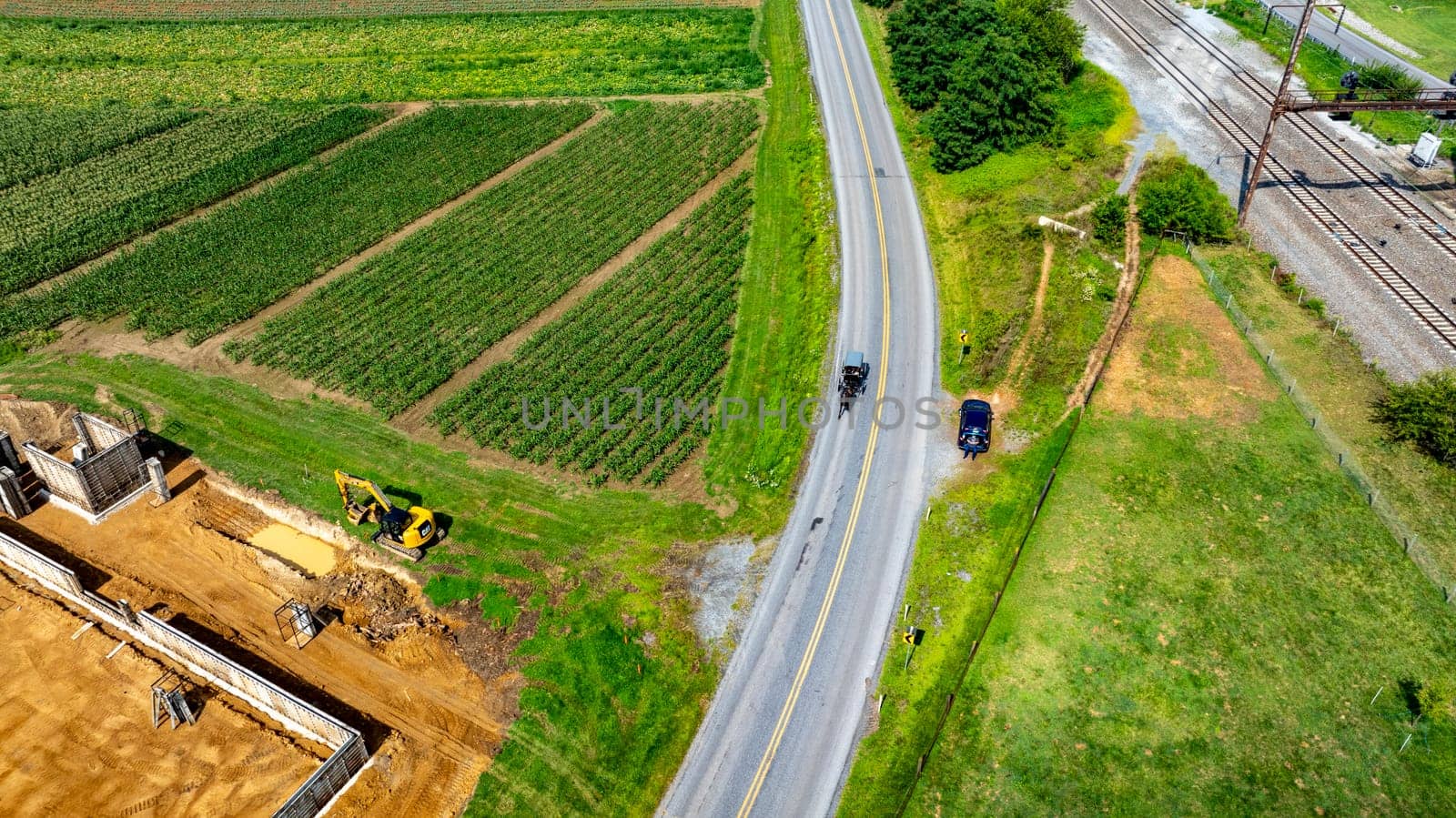 An Aerial View of Farmland with an Amish Horse and Buggy, on Road, with Railway, and Construction Site