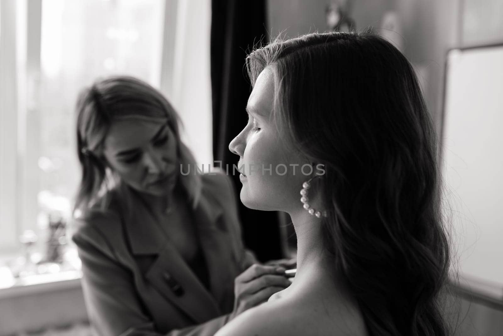 Backstage of photo shoot: Make-up artist applies makeup on beautiful white model.