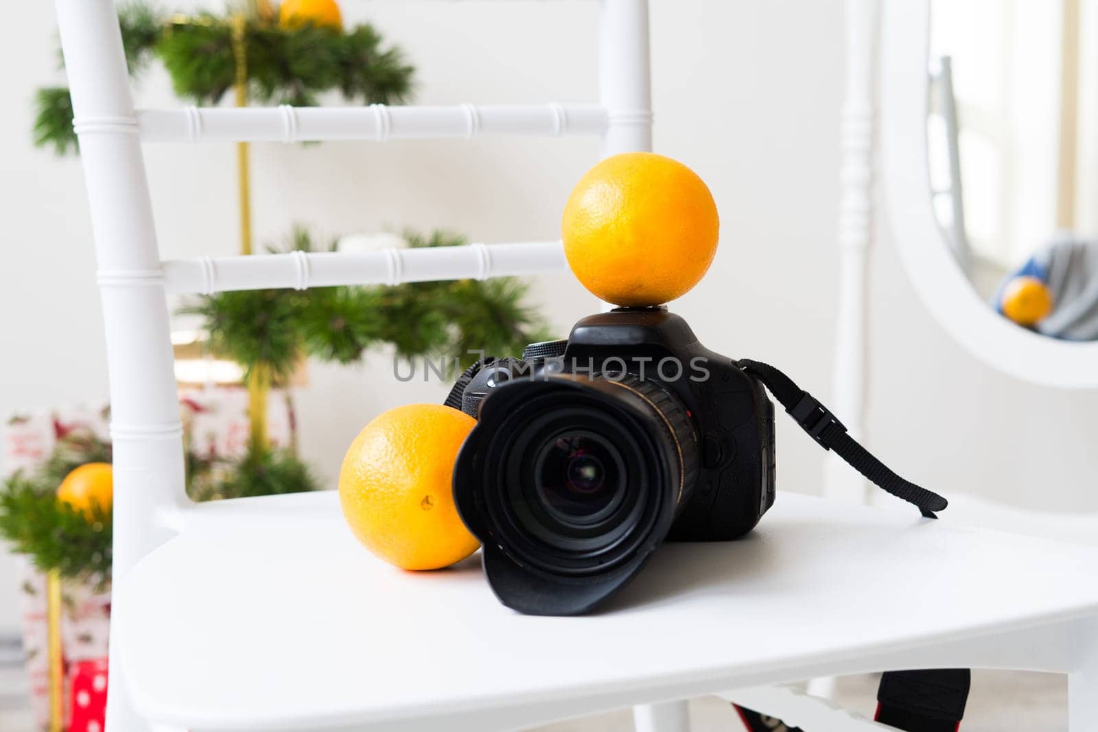 Photographer's equipment with Christmas decor on white chair by Zelenin