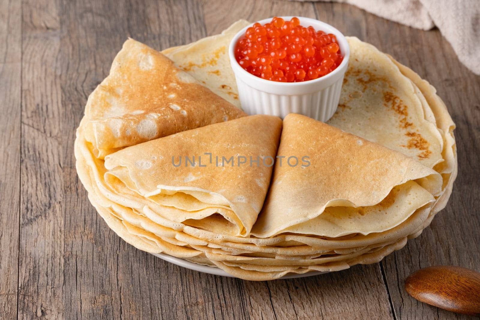 Pancakes with red caviar on a wooden table.