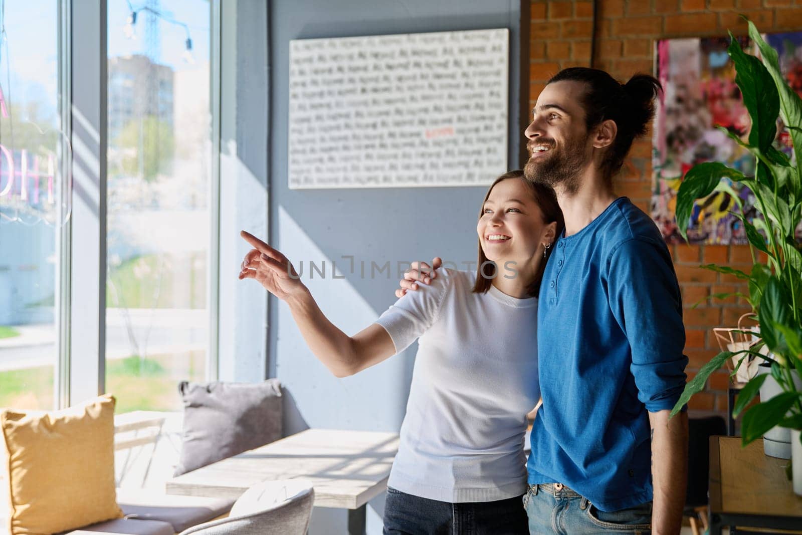 Young happy couple hugging together looking out the window. Love, friendship, romance, relationship, happiness, lifestyle, people concept