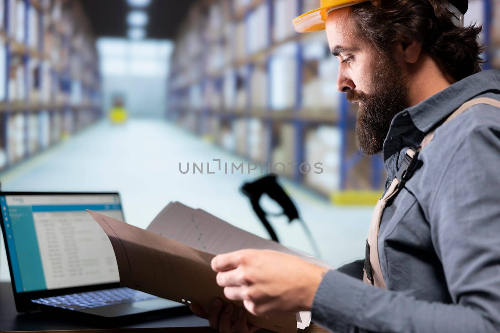 Industrial worker reading shipment invoice details in warehouse, supervising dispatch notes and order receipts in folder. Facility engineer working on supply chain management and quality control.