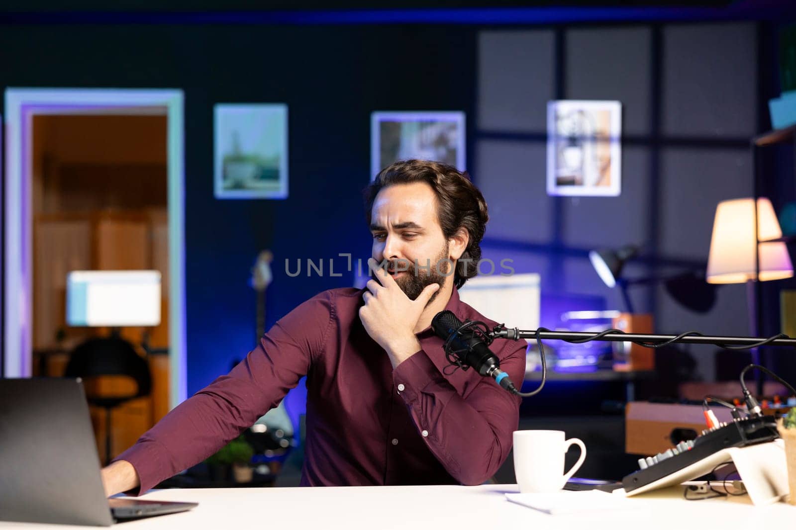 Man reading from laptop in studio, looking perplexed at recent news headlines, sharing opinions with audience. Show host talking with subscribers, feeling shocked by information he found online