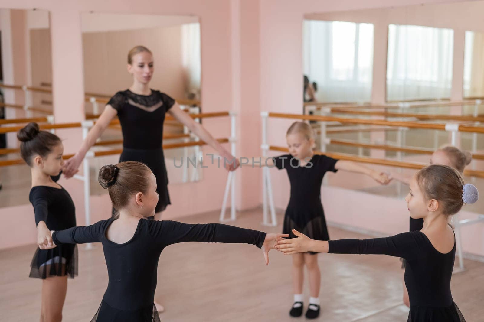 Children's ballet school. Caucasian woman teaching ballet to little girls