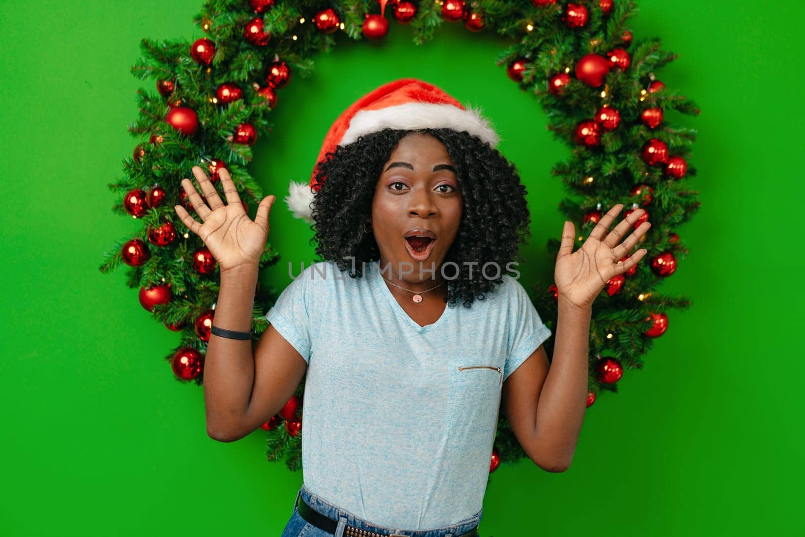 African woman smiling standing against Christmas wreath decor at home portrait