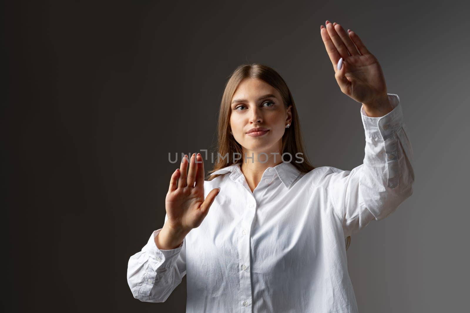 Young female entrepreneur touching virtual screen against grey studio background, close up