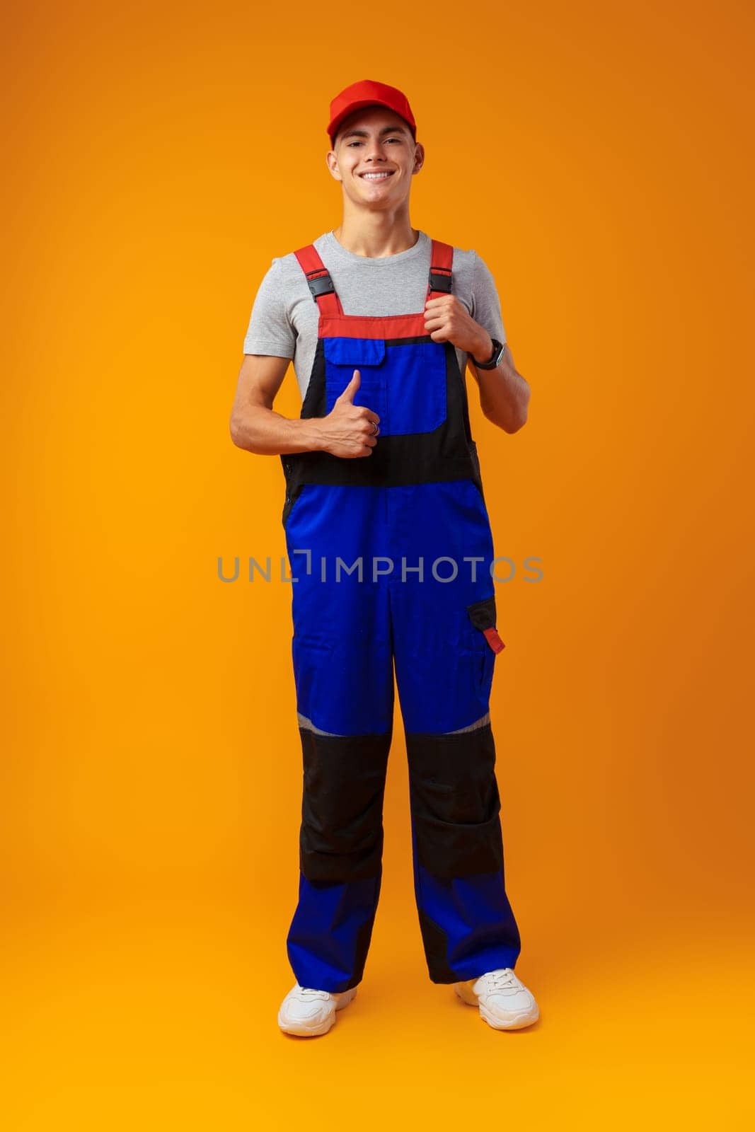 Full length shot of a young male worker in uniform on yellow background in studio