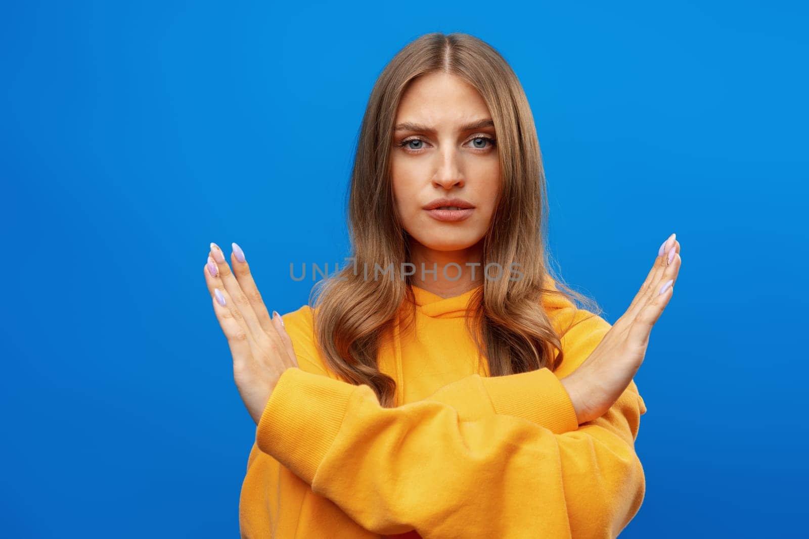 Portrait of attractive girl showing reject sign with crossed arms in studio, close up