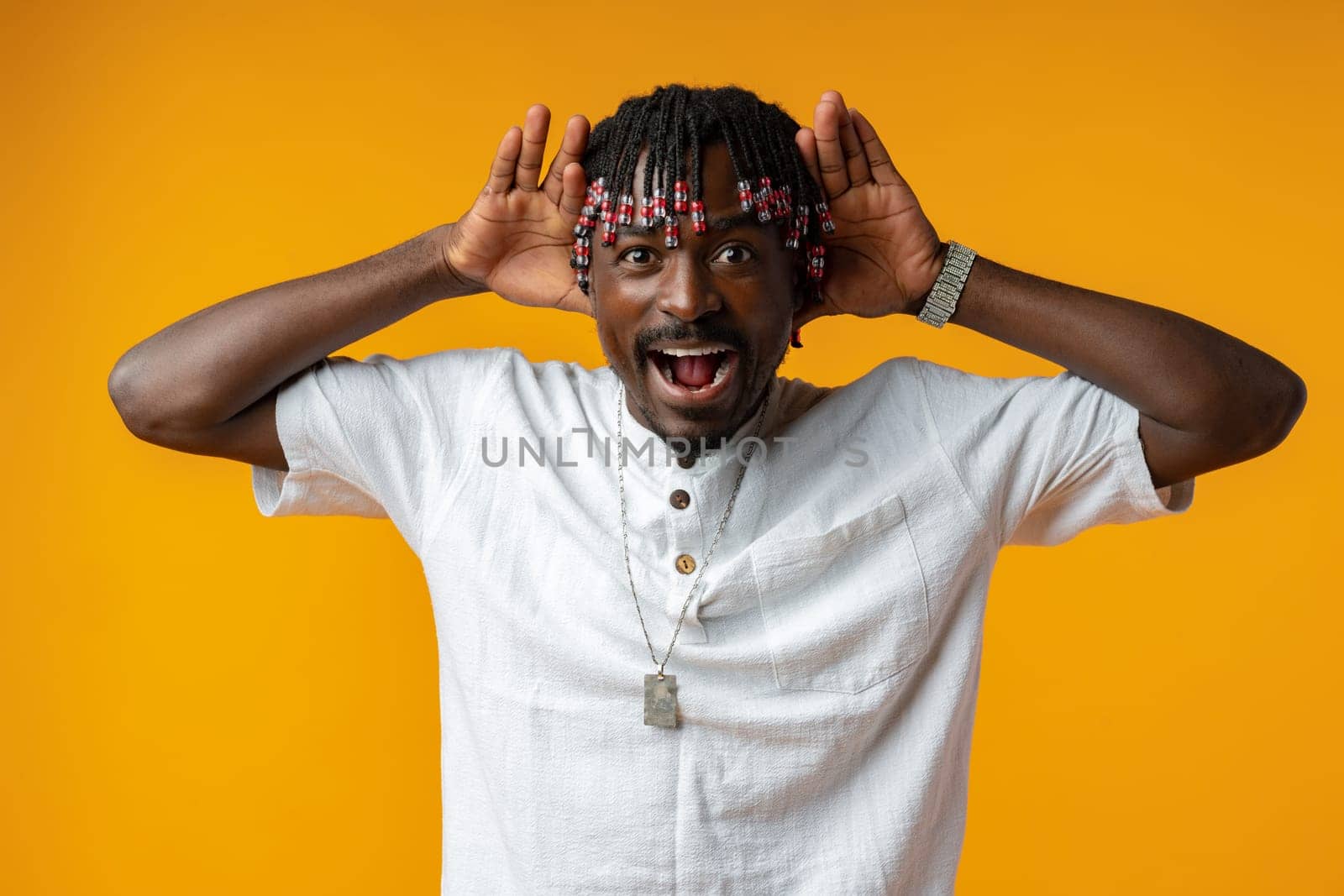 Shocked african man opening mouth widely on yellow studio background, close up