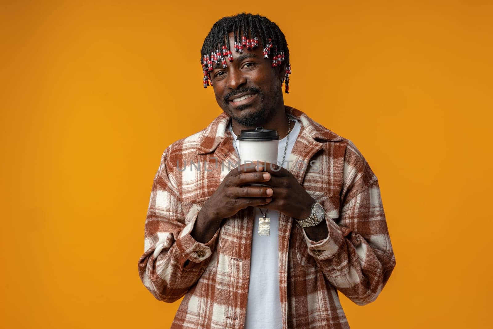 Young african man holding cup of take away coffee over yellow background close up