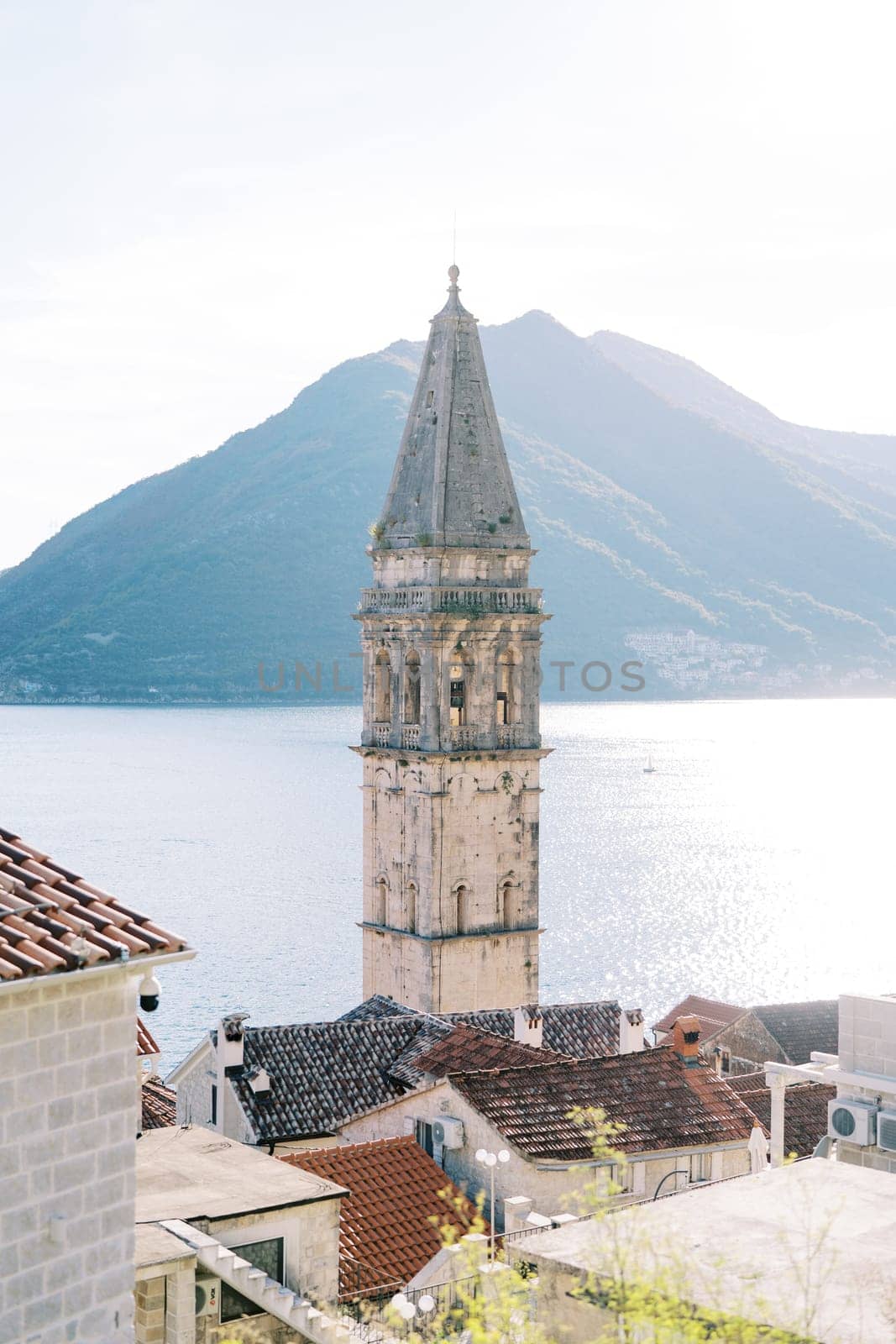 Bell tower of the Church of St. Nicholas on the shore of the Bay of Kotor against the backdrop of the mountains. Perast, Montenegro. High quality photo