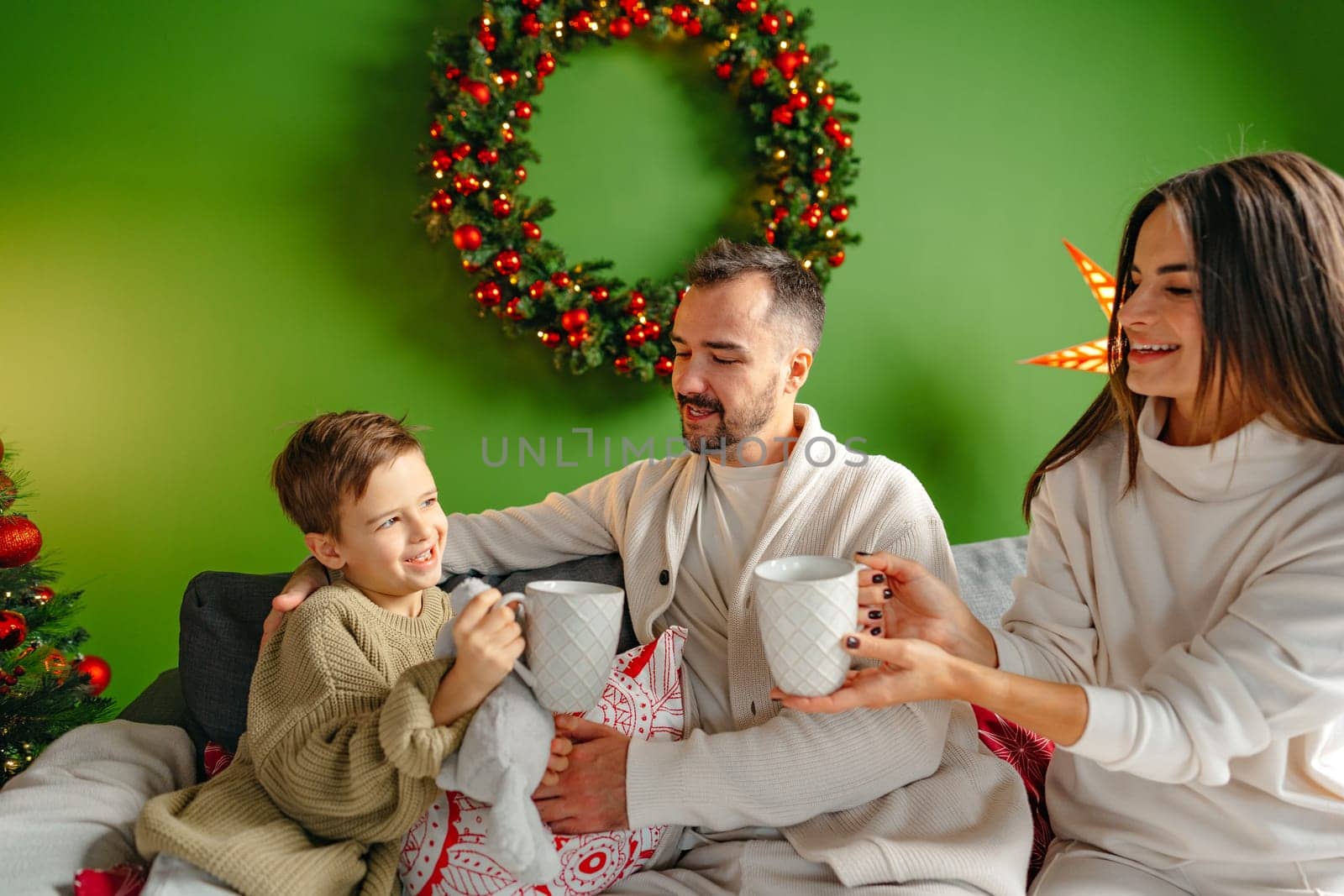 Happy young family sitting on sofa and relaxing at home at Christmas time