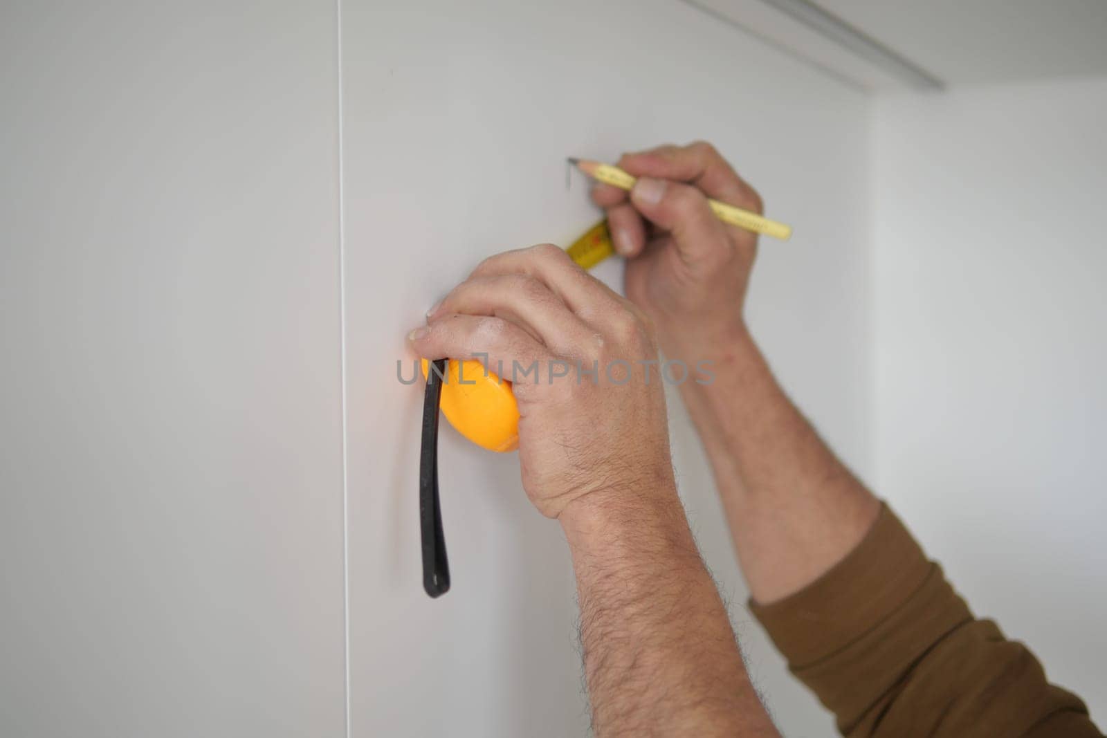 Man measuring wall with a tape measure .