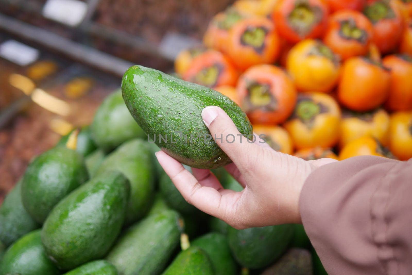 young woman hand holding avocado shopping at retail store .