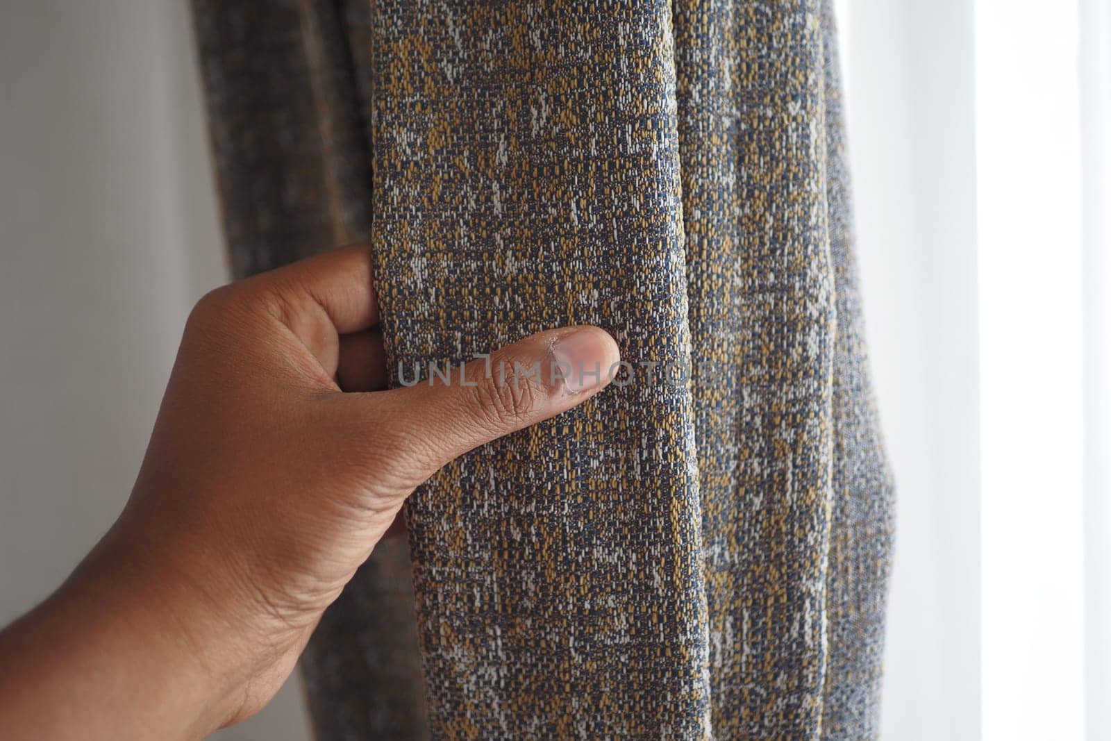close up of holding a gray fabric curtain.,