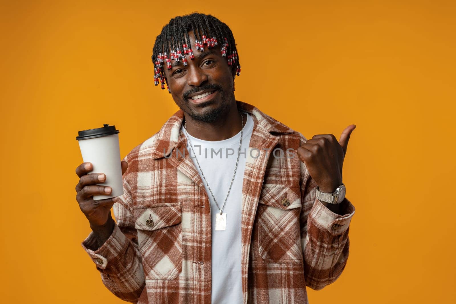 Young african man holding cup of take away coffee over yellow background close up