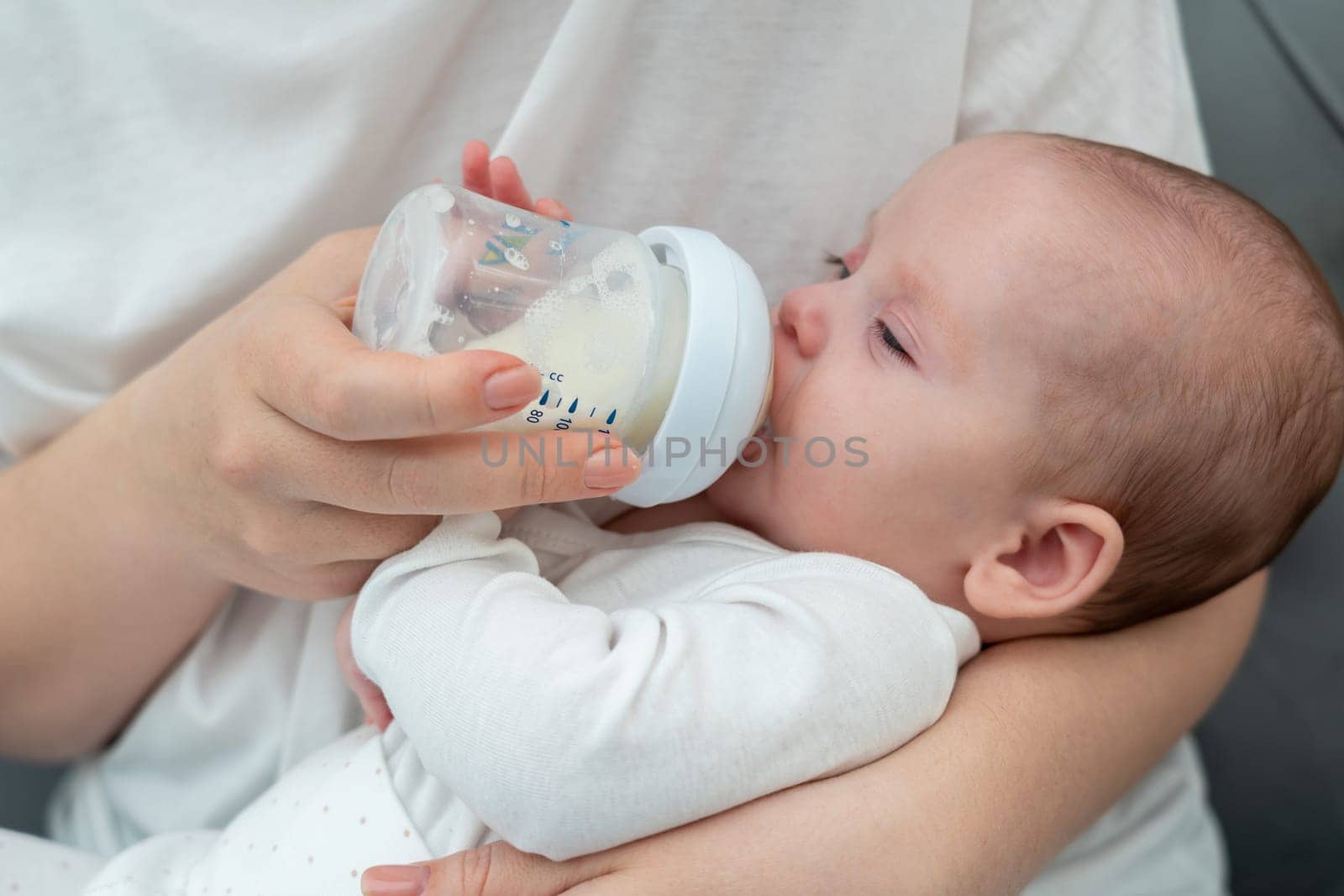 Tender moment of a mother holding and bottle-feeding her baby, capturing the simple joys of