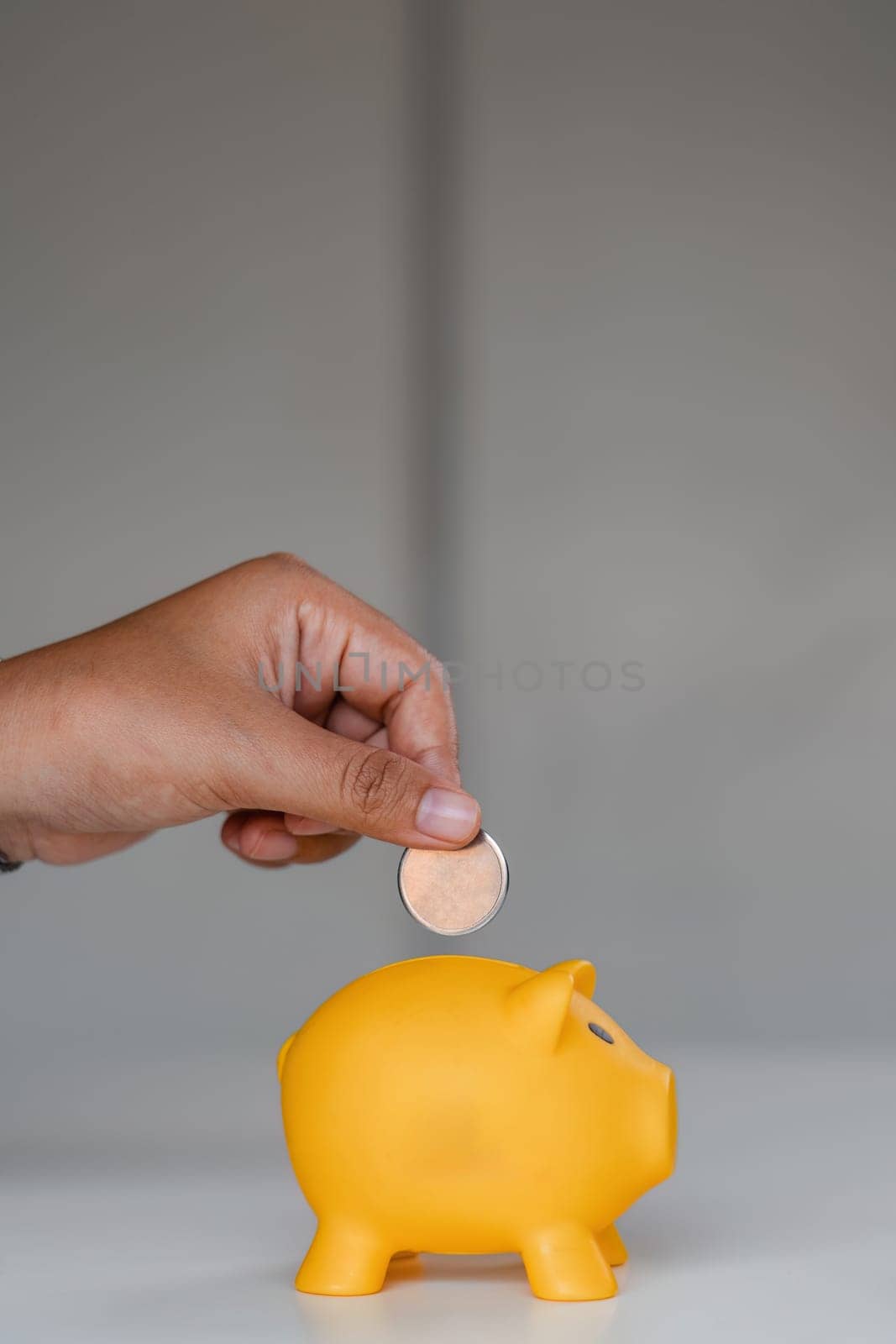Close up woman puts coins in a piggy bank with a pile of coins to save money..