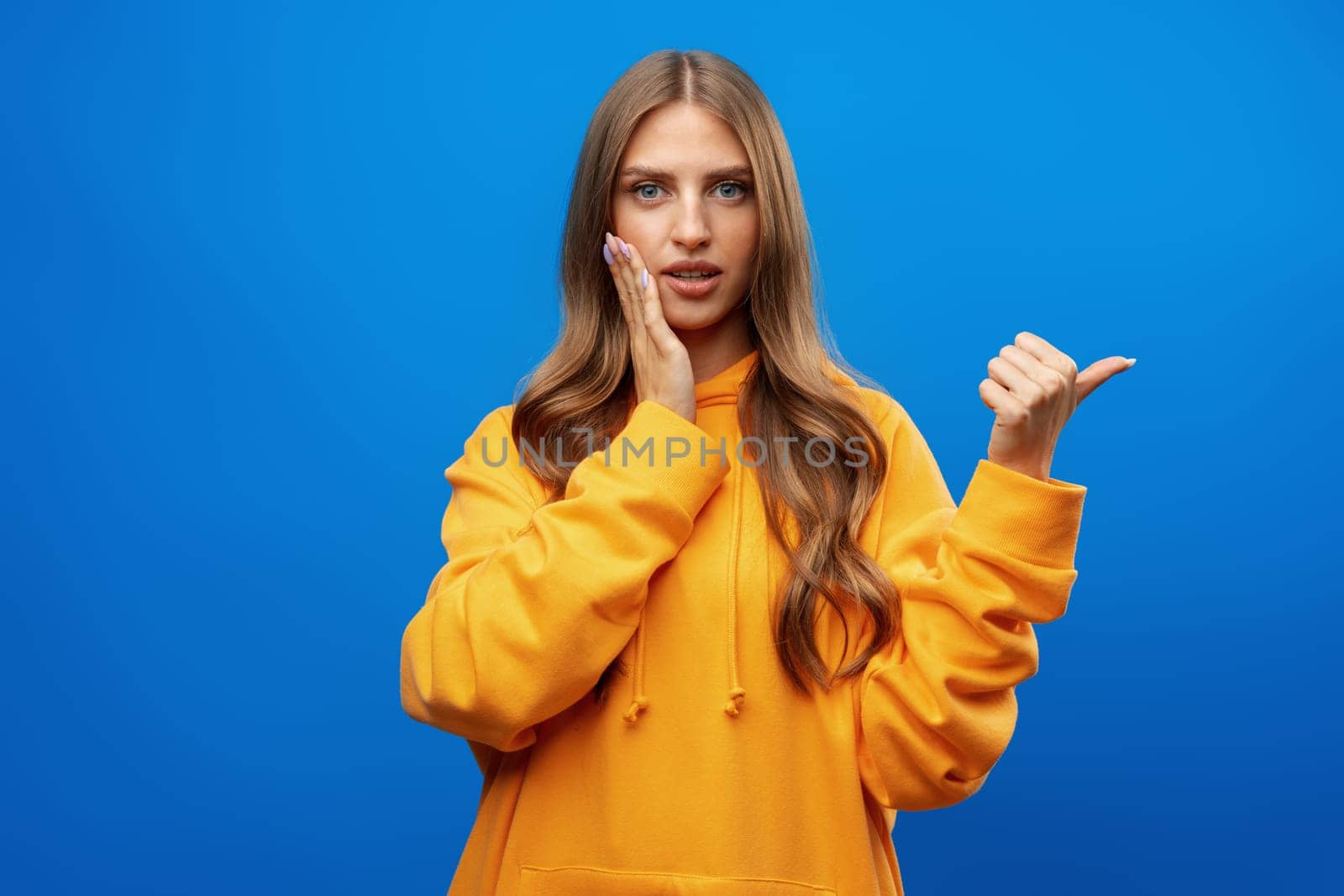 Young pretty woman pointing at copy space in photo studio