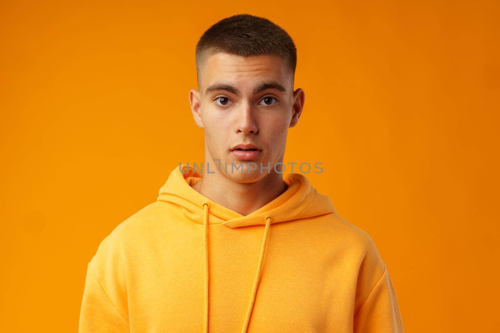 Young handsome man shocked with surprise expression standing over yellow background in studio