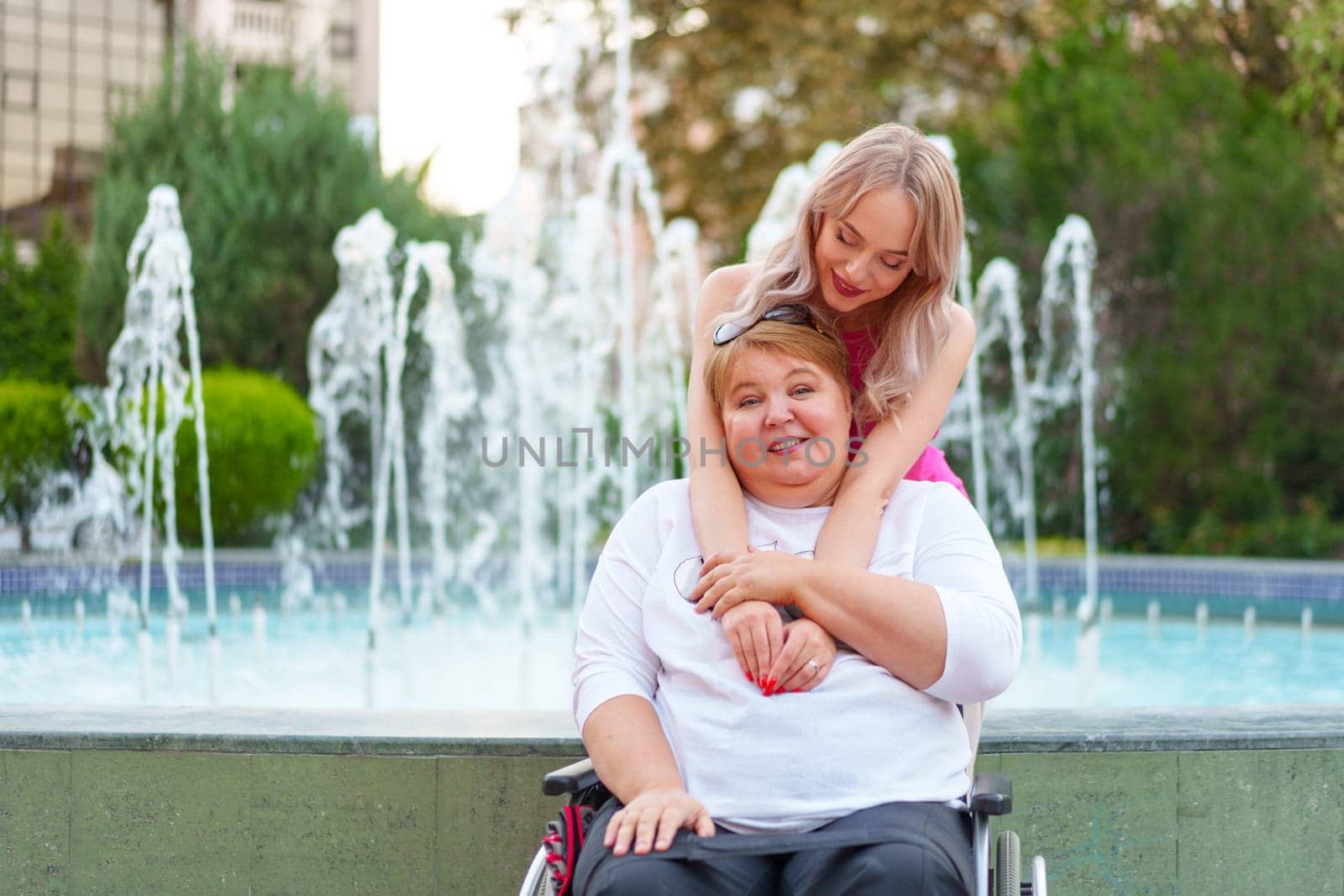 Young daughter taking care of her mother with disability sitting in wheelchair, portrait