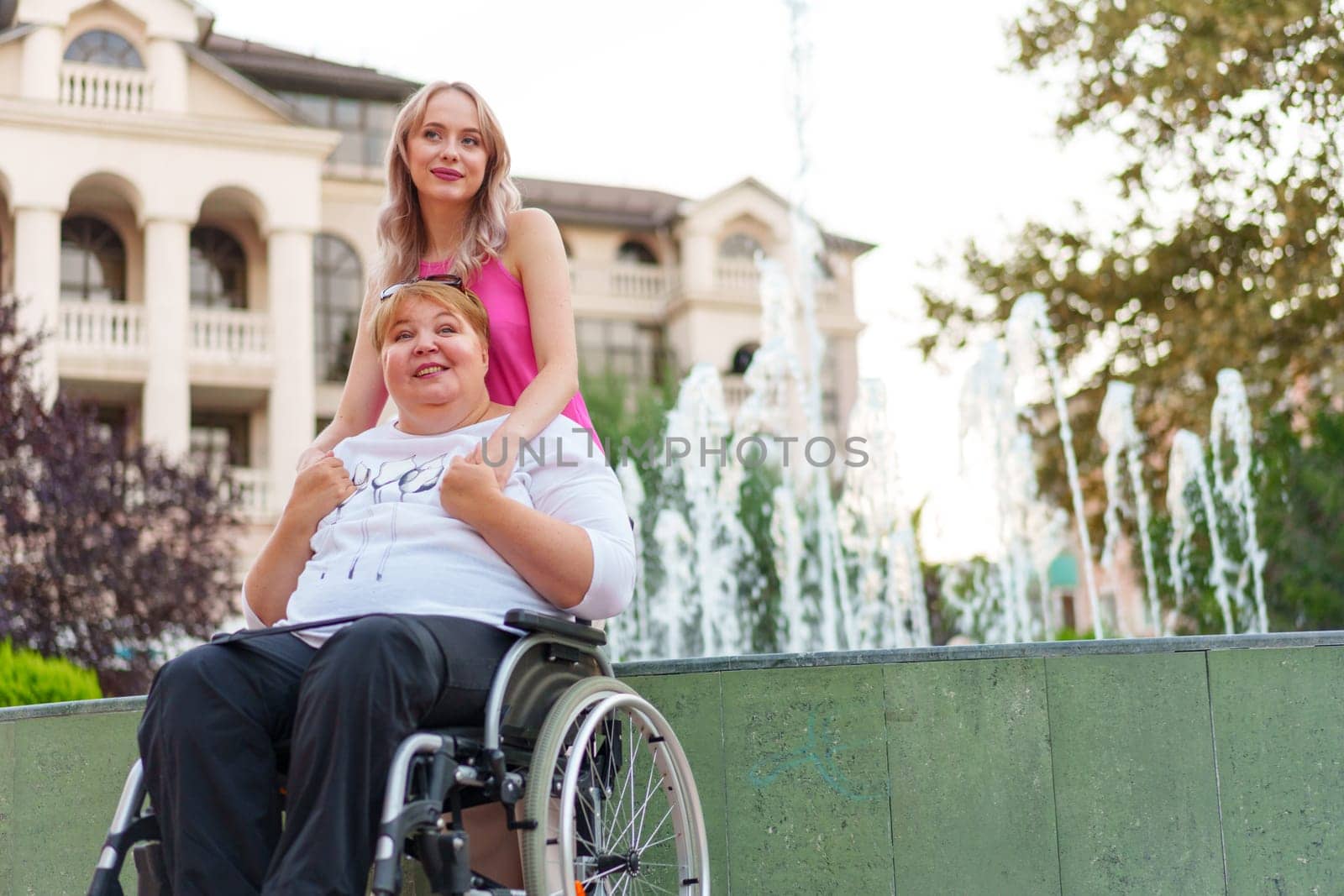 Young daughter taking care of her mother sitting in wheelchair, portrait
