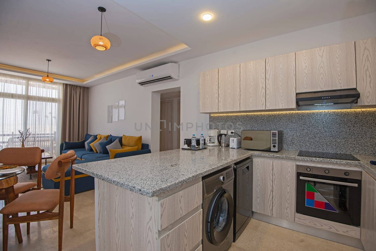 Living room lounge area in luxury apartment show home showing interior design decor furnishing with balcony terrace and open plan kitchen