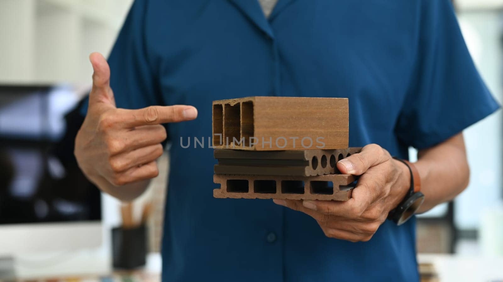 Cropped shot unrecognizable architect holding sample of wooden panel for furniture.