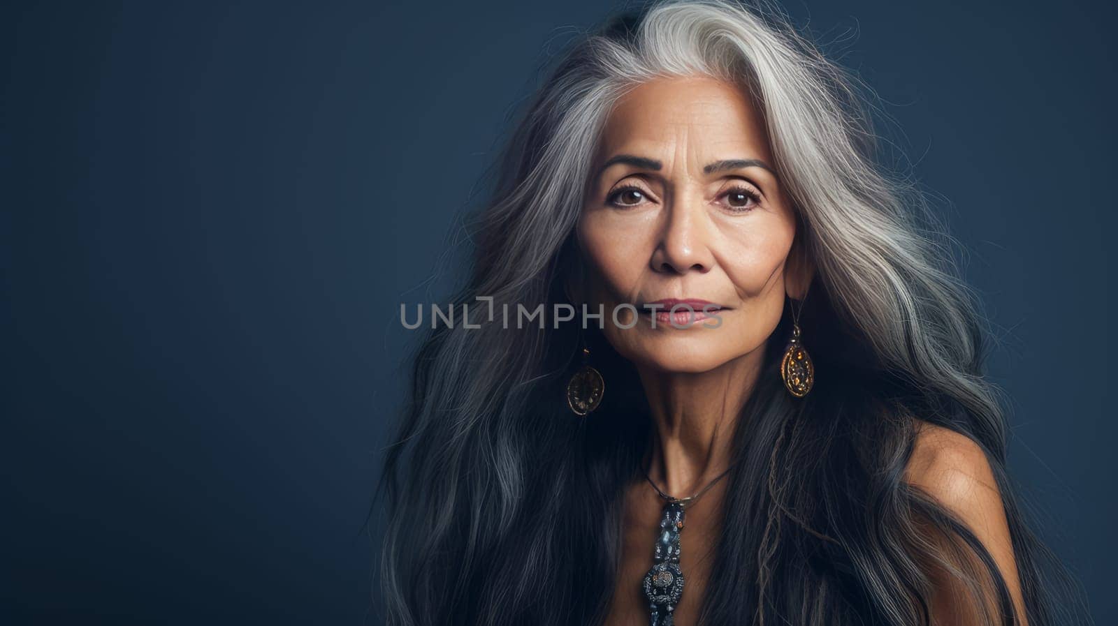 Elegant, elderly, chic latino, Spain woman with gray long hair and perfect skin, blue background, banner. Advertising of cosmetic products, spa treatments, shampoos and hair care products, dentistry and medicine, perfumes and cosmetology for women