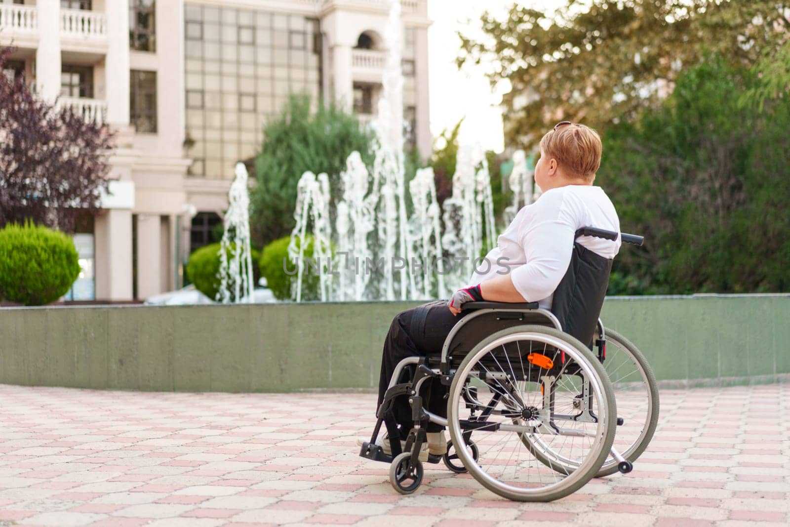 Mature woman sitting in wheelchair outdoors by Fabrikasimf