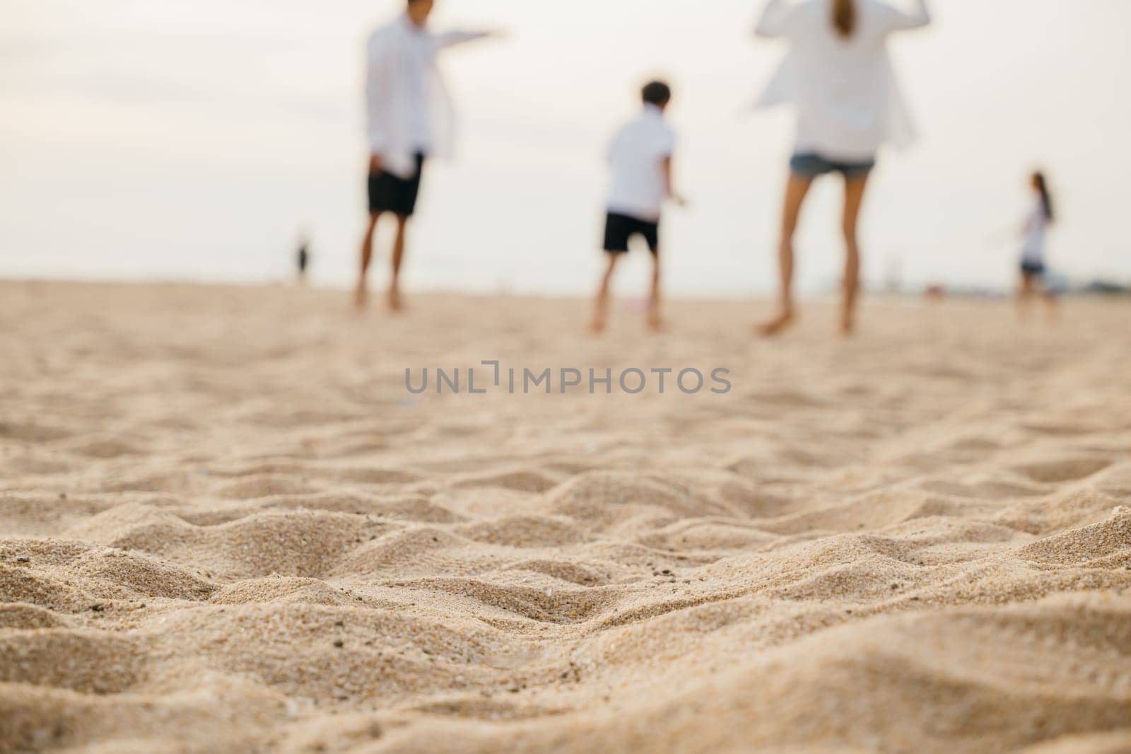 Smiling father and mother with son and daughter having fun on the beach. Running playing and laughing creating cheerful moments of family bonding and joy during summer. Family on beach vacation by Sorapop