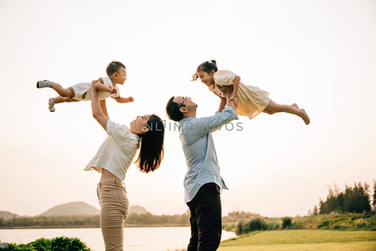 On a tropical vacation, a happy couple enjoys a moment of playful fun, as the father and mother throw their baby up in the air against a beautiful sunset sky. family enjoys a carefree vacation moment