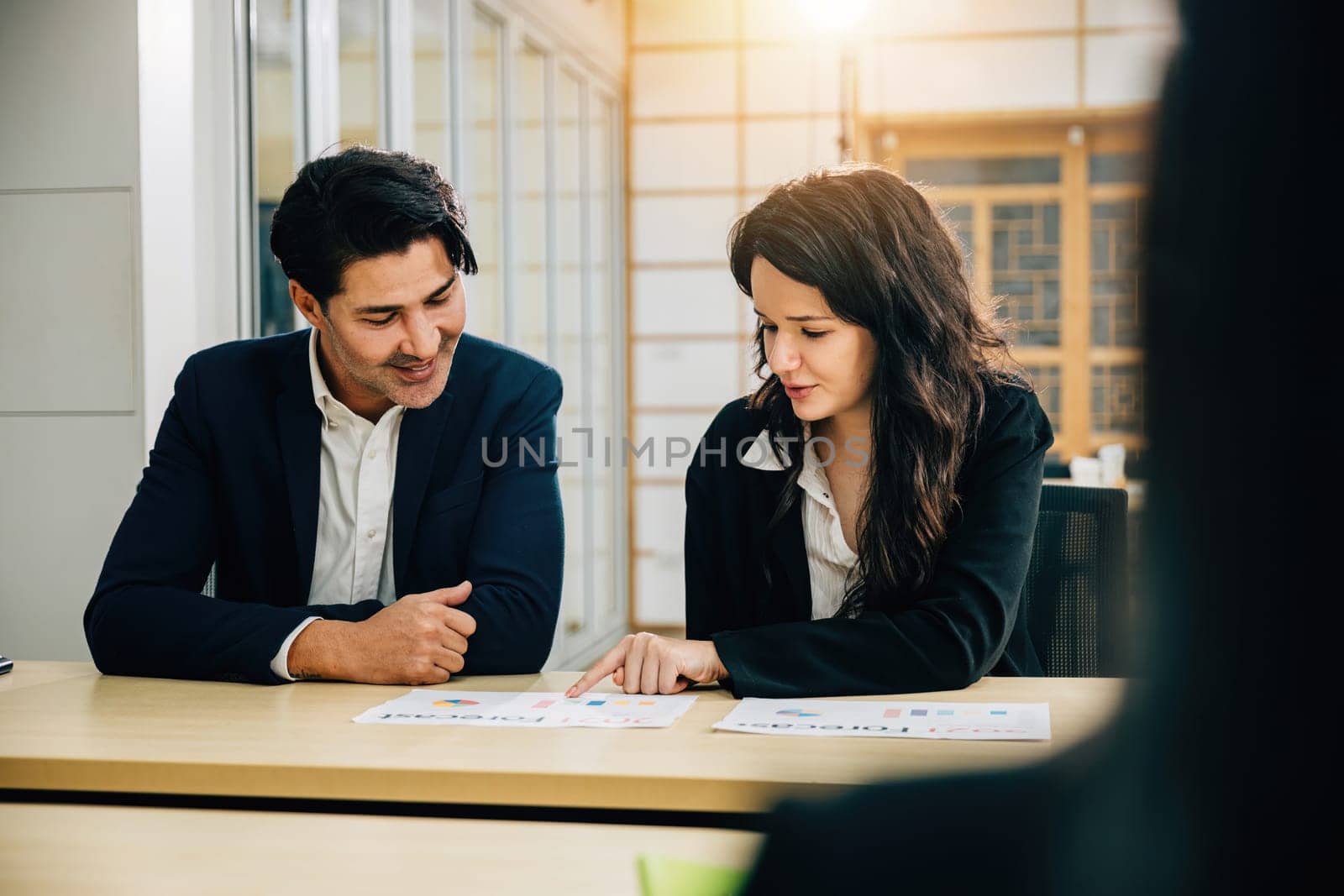 Business partners meet at the office, discussing business strategy and financial success. Their teamwork, documents, and graph analysis are a testament to their collaboration.