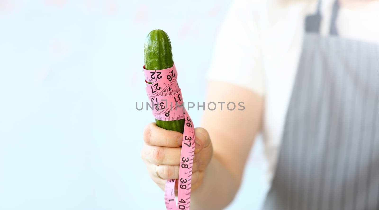 Chef Holding Centimeter Wrapped Ripe Cucumber. Culinary Man Measure Green Cuke Coiled in Centimetre. Man in Apron Standing with Ingredient in Hand. Vegetable Measurement Horizontal Photography